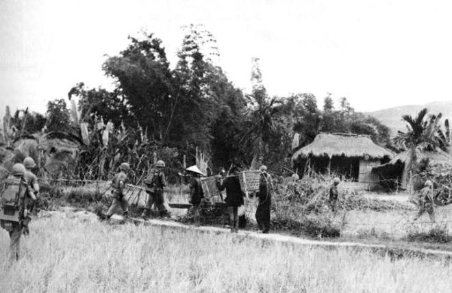 In one of the first extensions of Marine positions into a populated area in May, Marines from the 2d Battalion, 3d Marines move into the hamlet of Le My. Three villagers watch the troops enter the village gate.