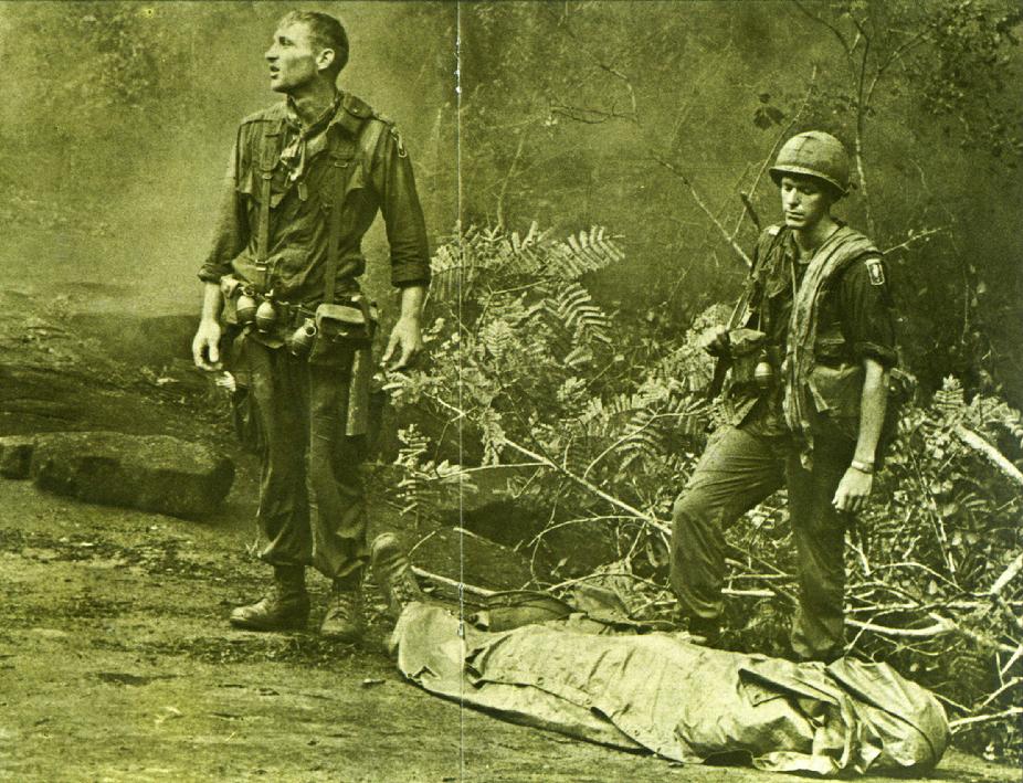 Ruediger Richter of the 4th Battalion, 503rd Infantry, 173rd Airborne Brigade, lifts his battle weary eyes to the heavens, as if to ask "Why?" Sergeant Daniel E. Spencer stares down at their fallen comrade. The day's battle ended, they silently await the helicopter which will evacuate their comrade from the jungle covered hills. Photo by Paul Epley (August 14th, 1966)